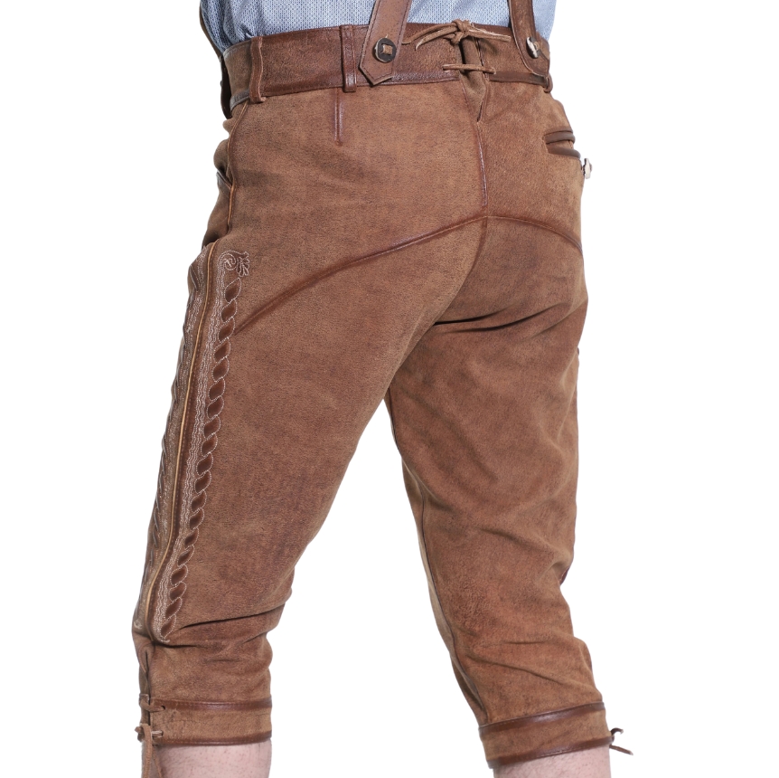 Rear view of rustic oak brown knee-length leather bundhosen featuring unique curved back seam stitching, suede texture, and tied cuffs at the knees.